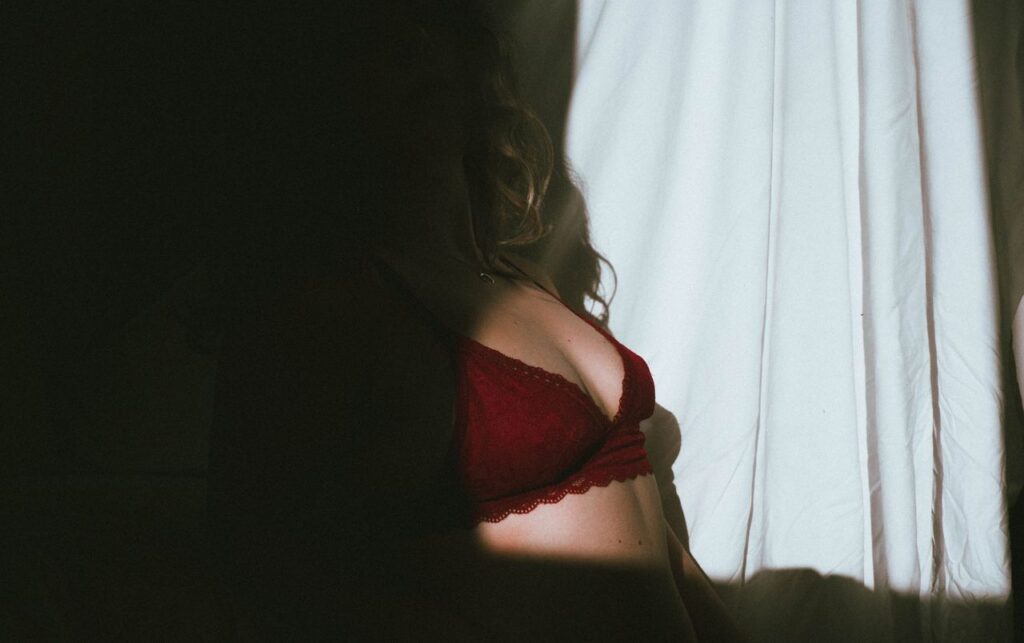 Artistic silhouette of a woman in red lingerie emphasizing shadows and light.